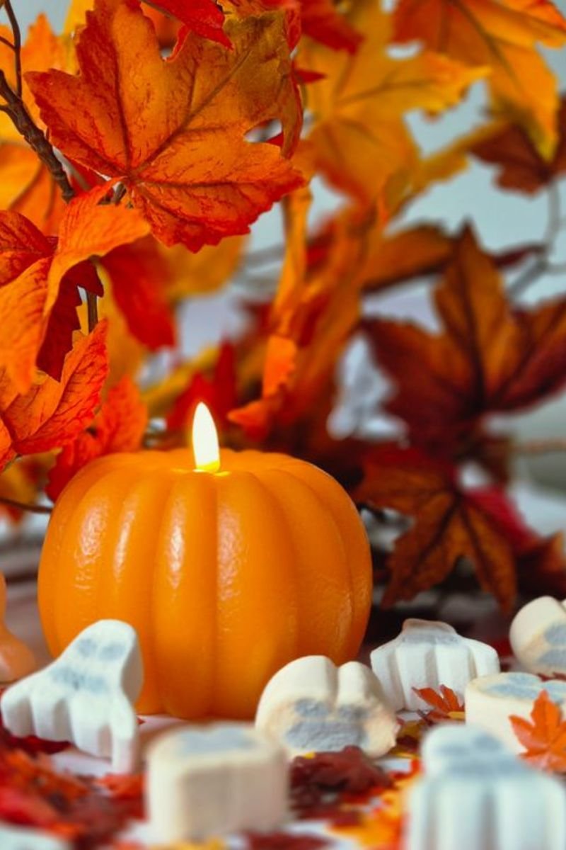 Abundant candlelit Thanksgiving tablescape pumpkins candles cranberries foliage linen