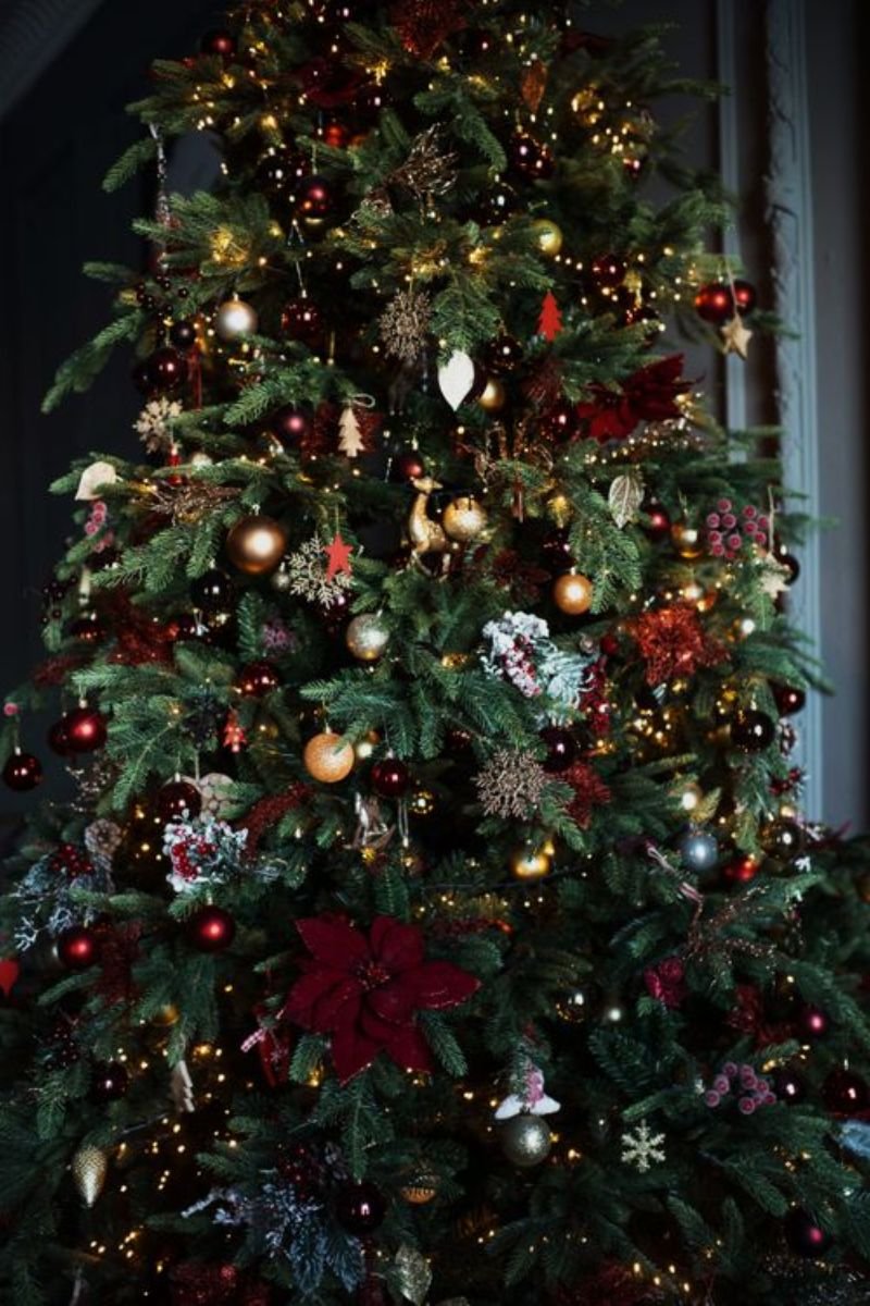 Christmas tree decorated in deep emerald green ruby red and sapphire blue jewel tone ornaments with gold accents