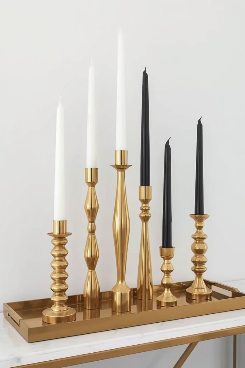 Gold candlestick holders at varying heights on a console table in a Neo Deco living room"