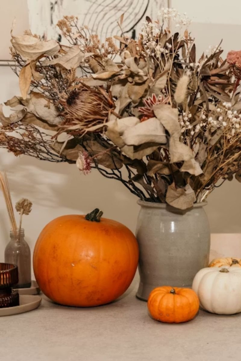 Hollowed pumpkin floral vessel dark dahlia pampas grass eucalyptus elegant Halloween