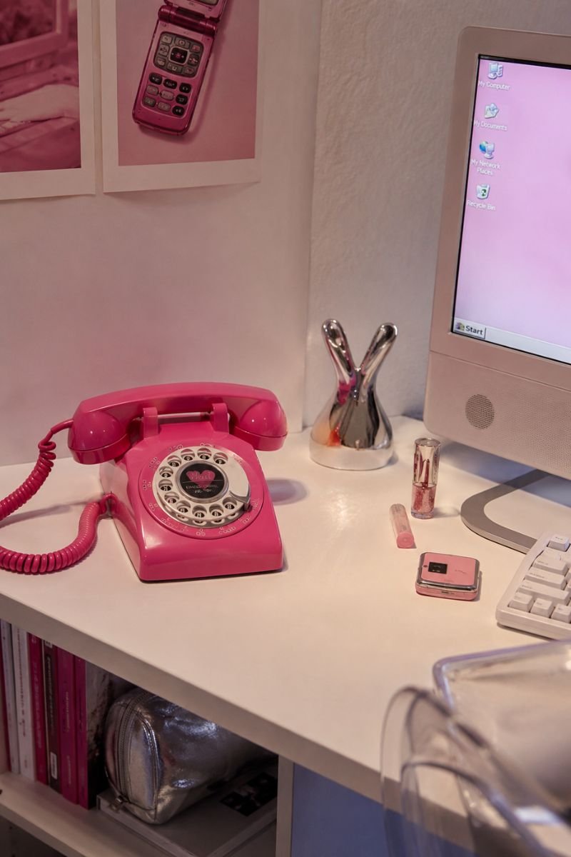 Hot pink retro telephone on white desk in Y2K bedroom