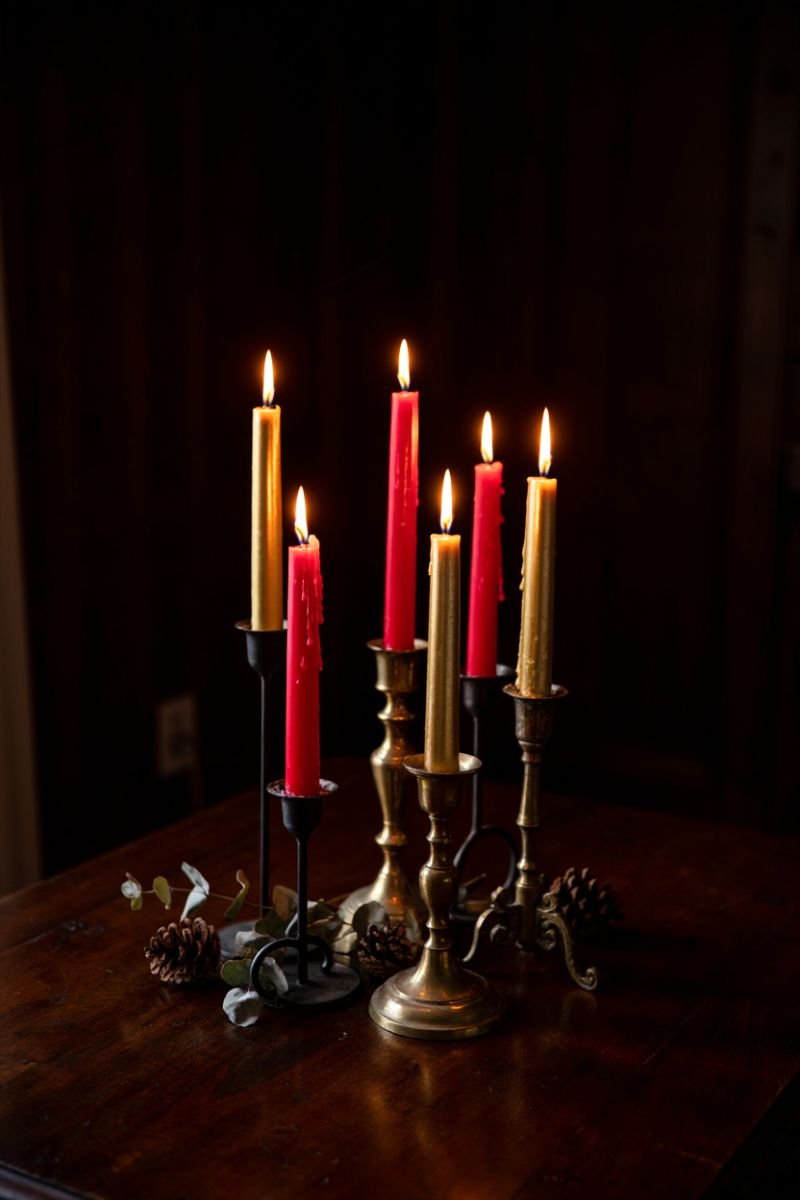 Mismatched brass and iron candlestick holders with red taper candles on a table
