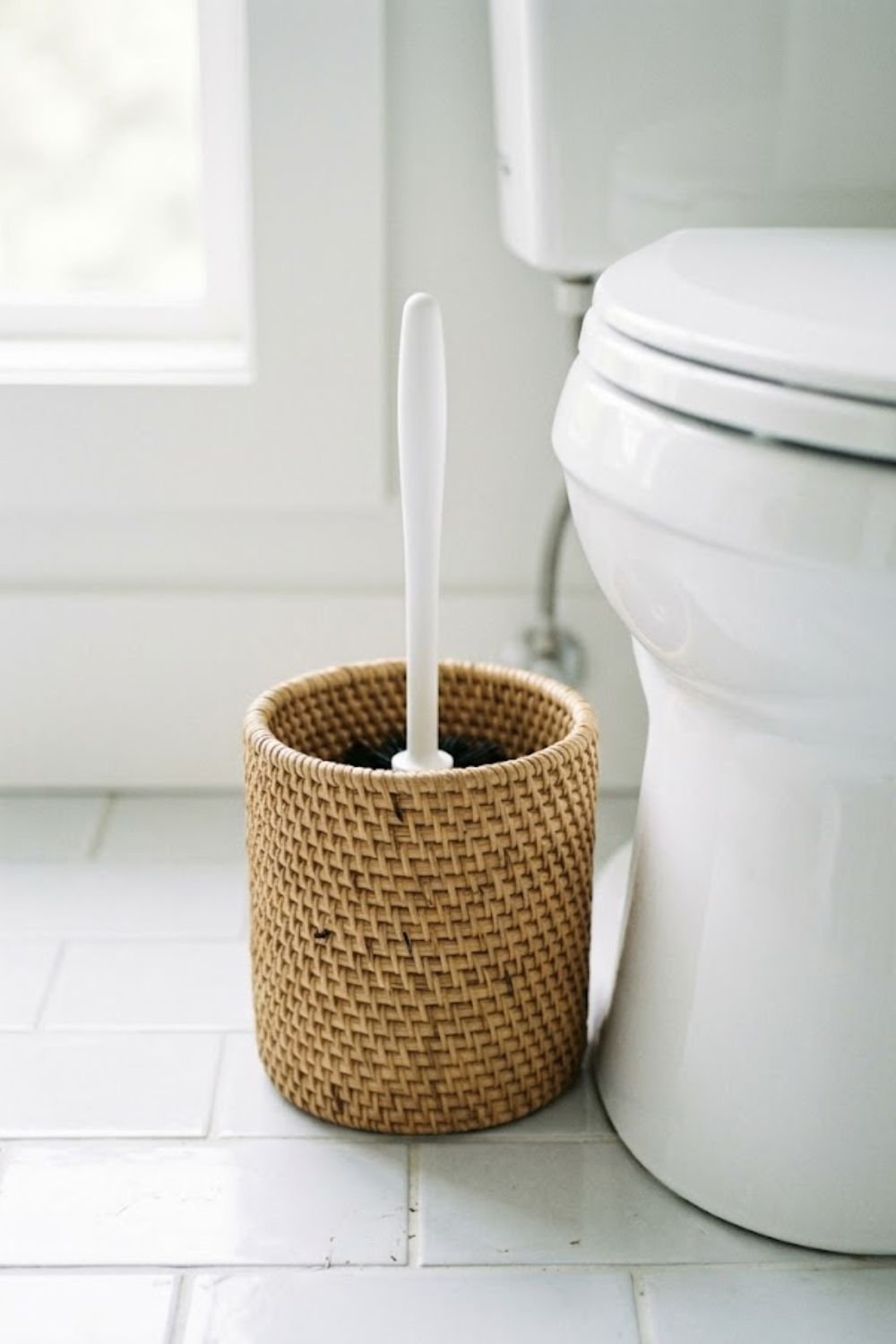 Rattan toilet brush holder beside a white toilet in a natural spa style bathroom