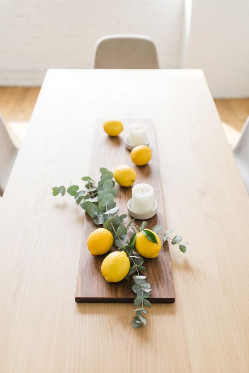 Simple summer dining table centerpiece with lemons candles and fresh herbs