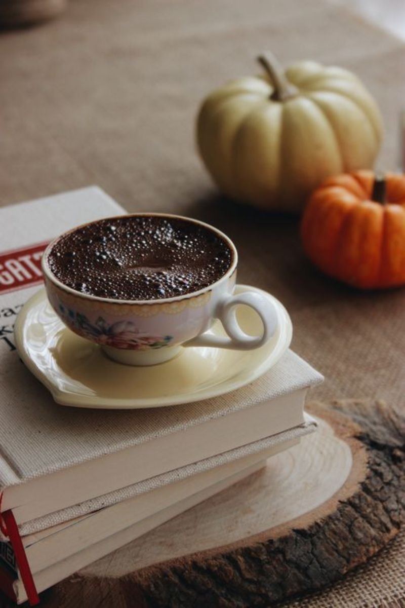 Stack of coffee table books topped with a mini pumpkin and small candle for fall styling 