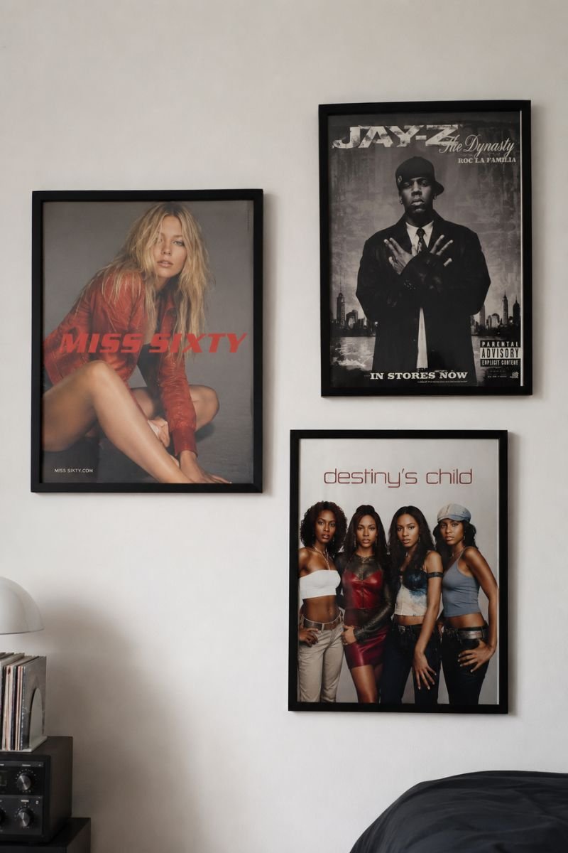 Three black-framed Y2K era posters on white bedroom wall