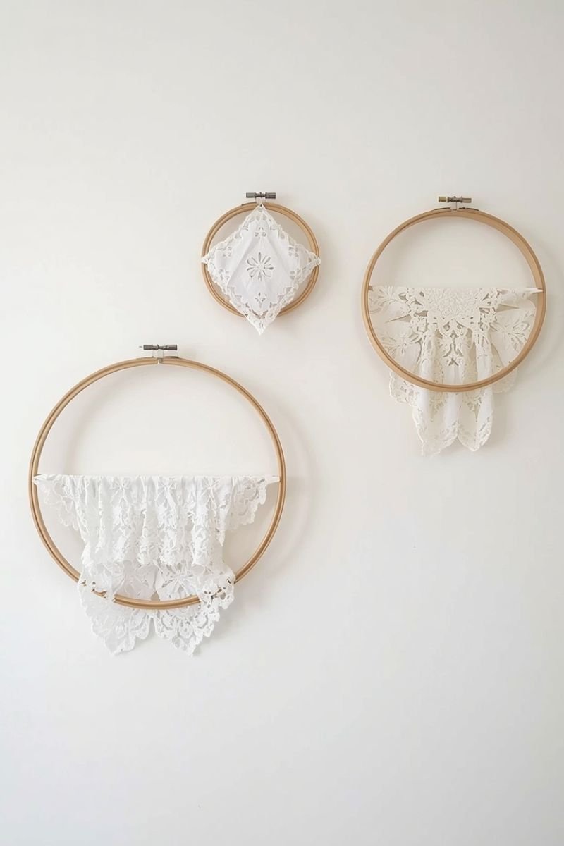Three wooden embroidery hoops with white doilies hung on a white wall