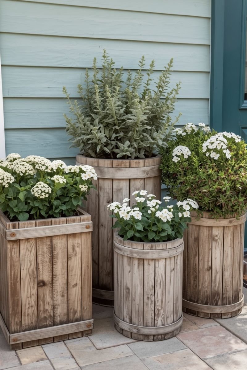 Weathered wood planters with white flowers and ornamental grasses on a summer porch