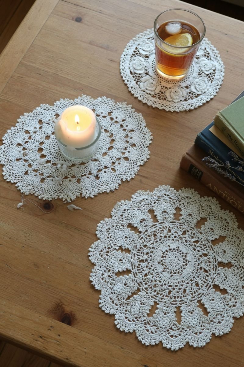 White doilies used as coasters on a wooden coffee table with candles