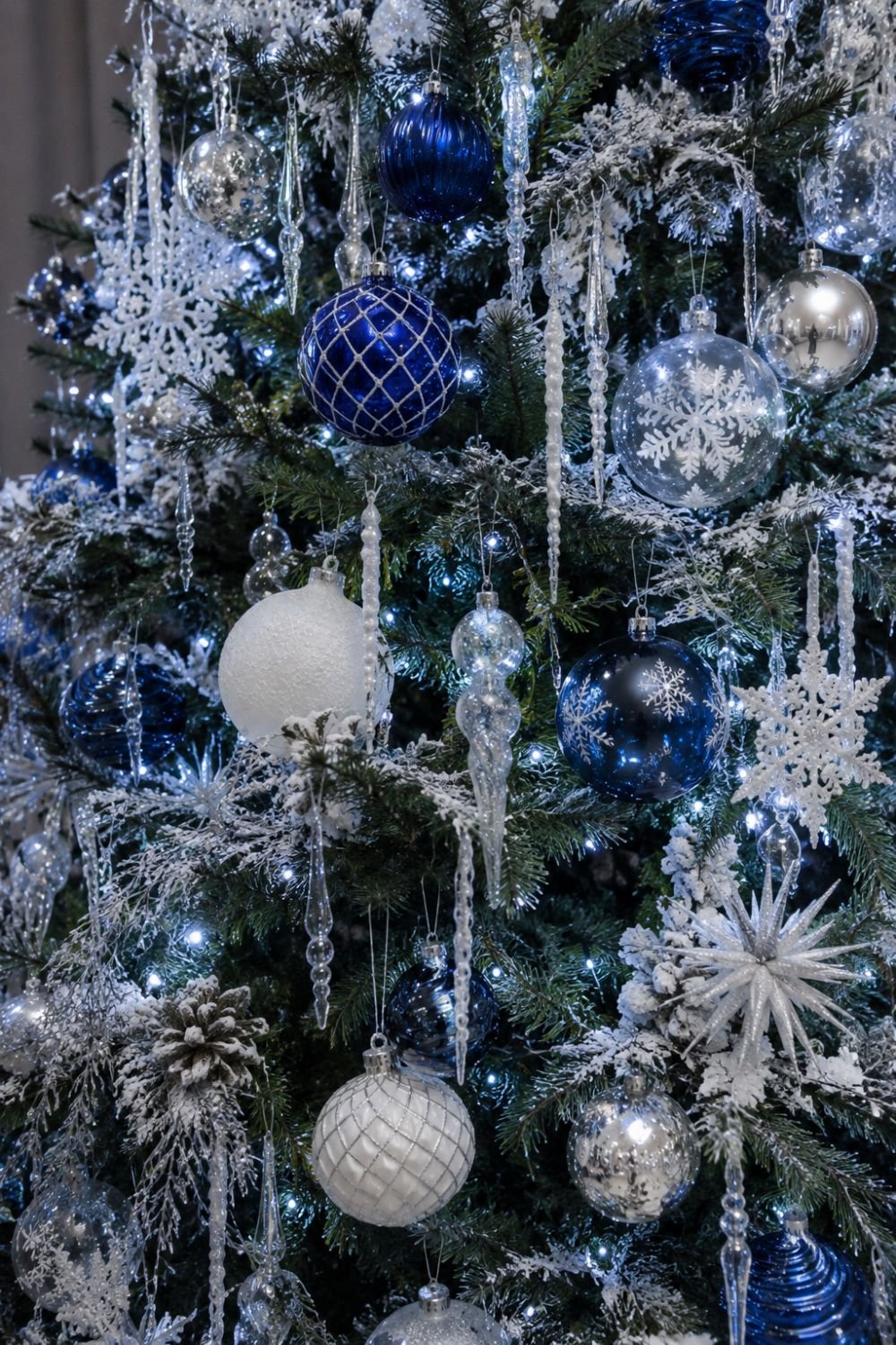 Blue glass ornaments and icicles creating sparkle on winter tree