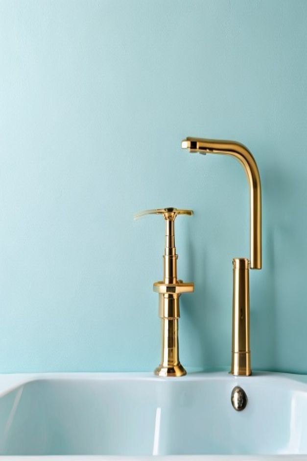 Brass faucet and hardware against a light blue bathroom wall