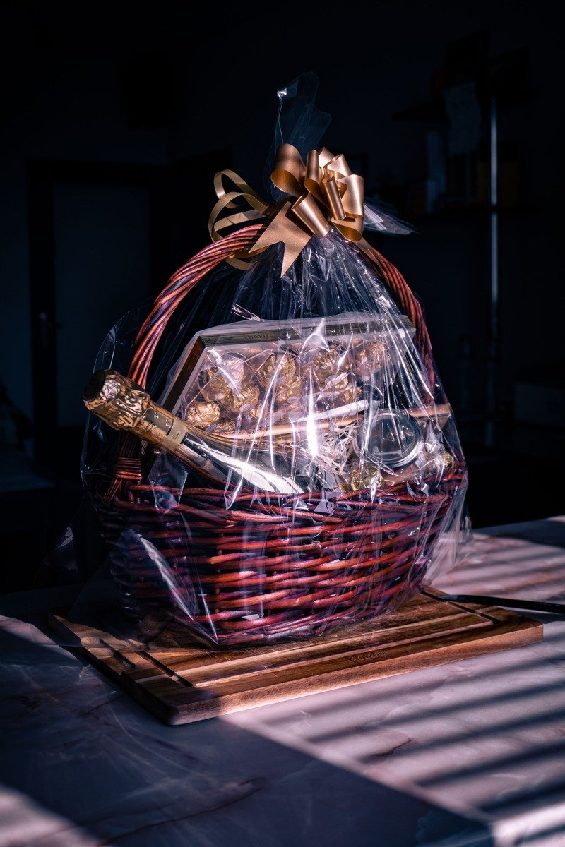 Christmas gift hamper wrapped in cellophane with a gold bow and chocolates