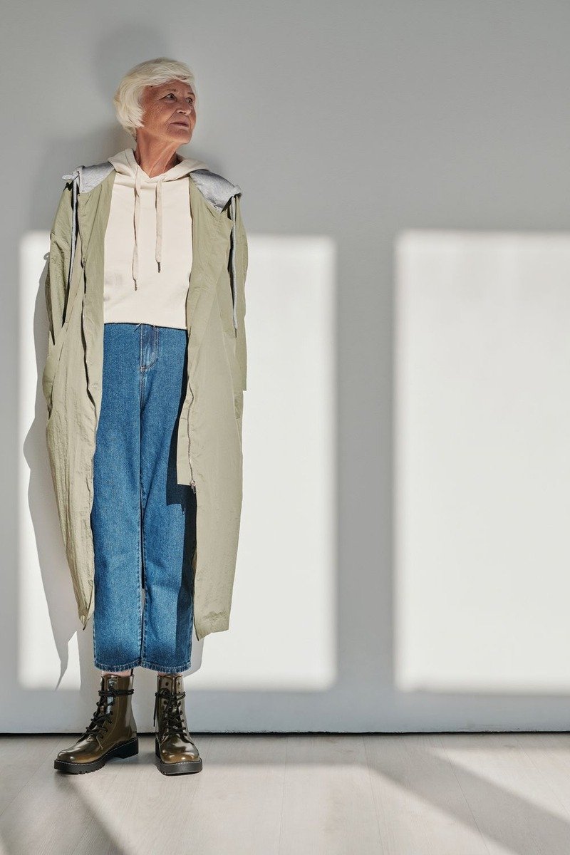 Woman over 50 in a long sage coat and wide leg jeans