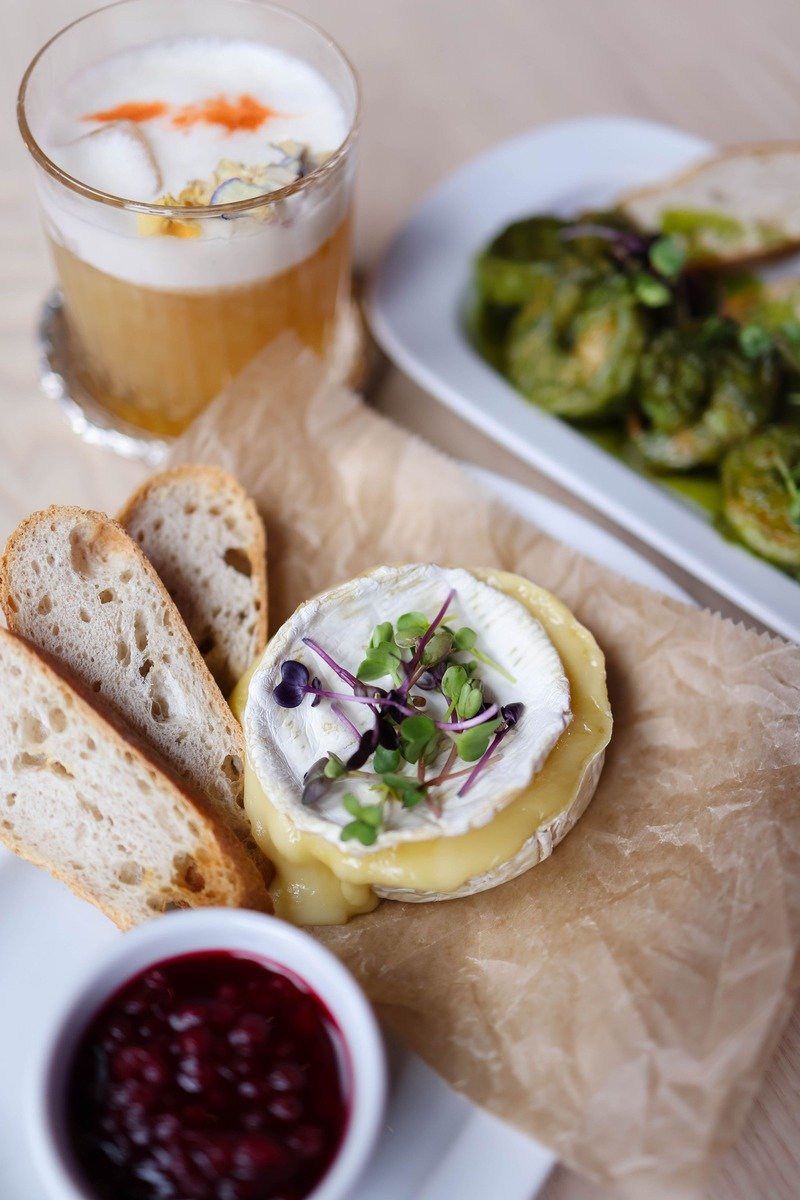 Baked brie with a bowl of cranberry sauce on a board