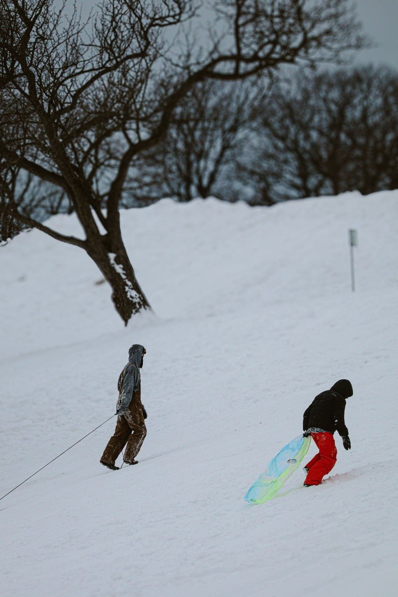 People with a sled on a snowy hill