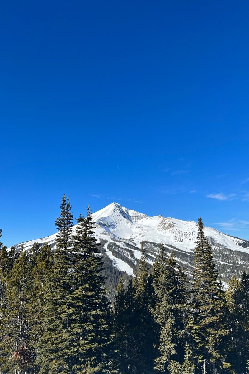 Snow-covered Montana ski peak with groomed runs under a blue sky