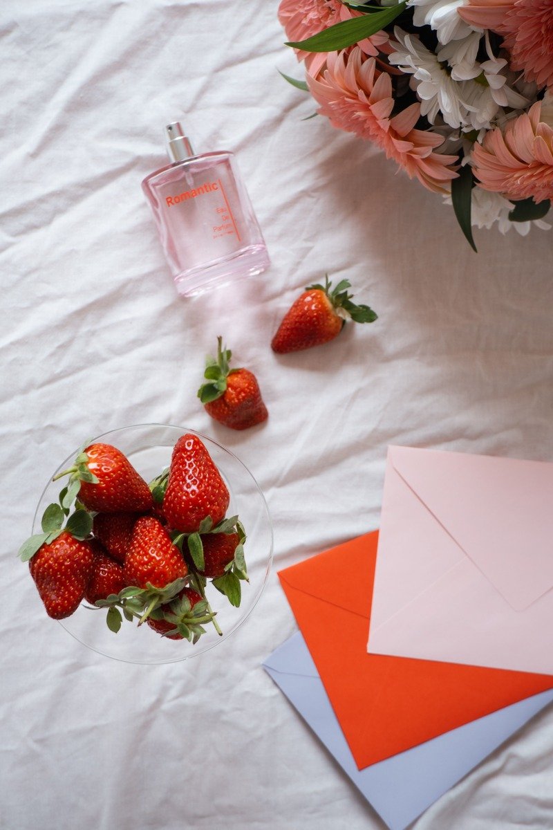 Perfume bottle beside fresh strawberries and vanilla