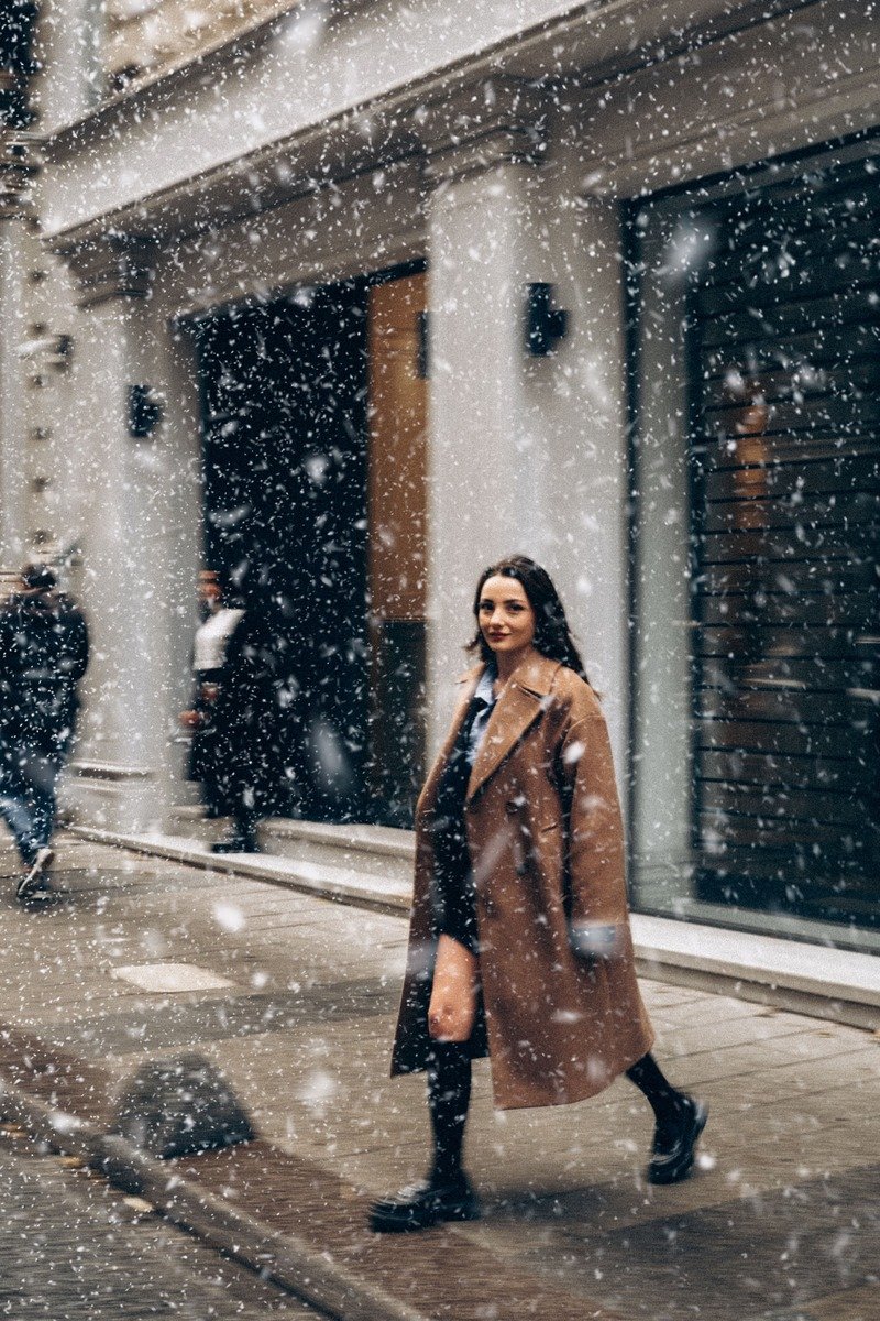 Woman in a long camel coat over a suit walking to work in winter