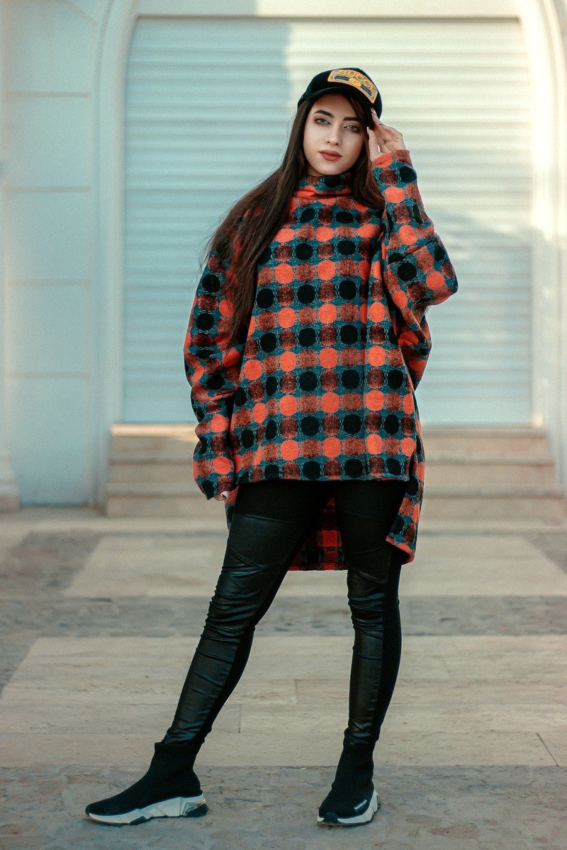 Woman in a long oversized sweater with black leggings and chunky sneakers