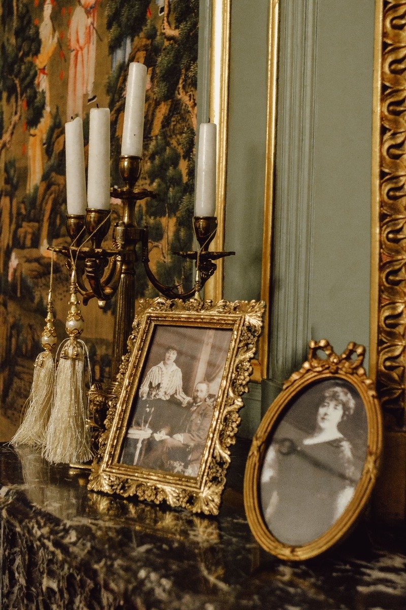 Layered art frames leaning on a fireplace mantel