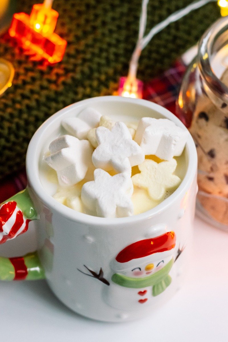 Snowman mug of hot chocolate with marshmallows and a cookie jar