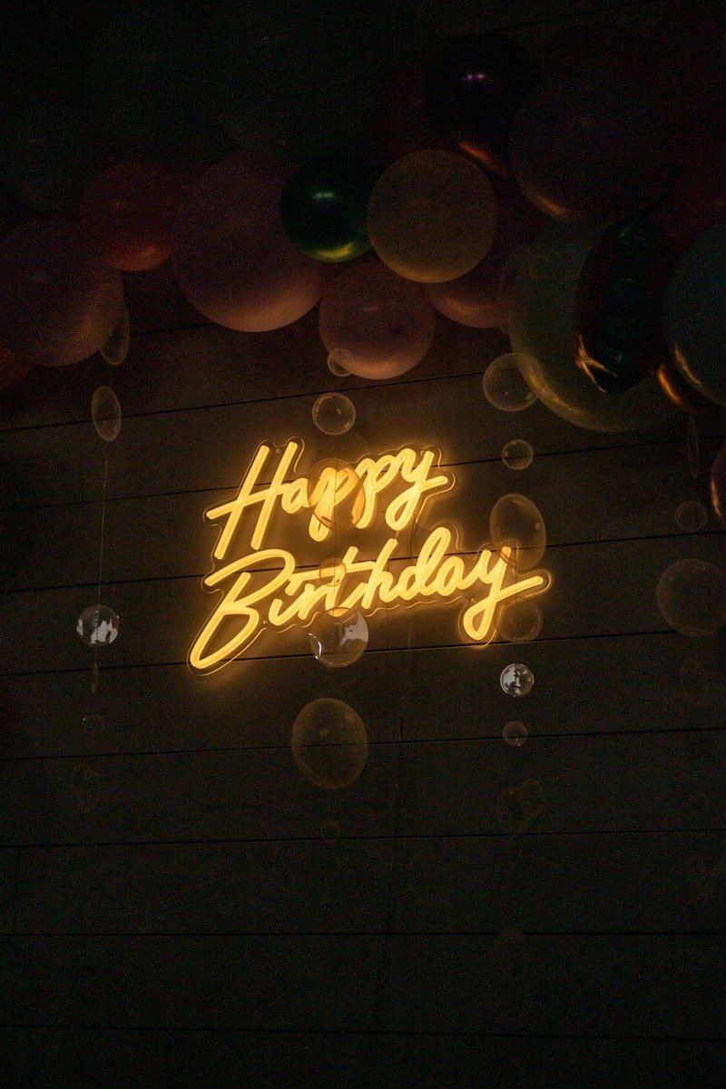 Neon happy birthday sign on a greenery wall at a party
