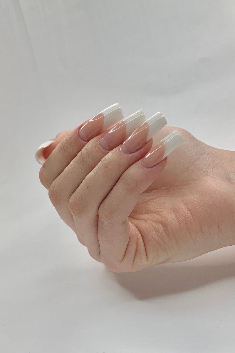 Classic white French-tip manicure, close-up of one hand on white background