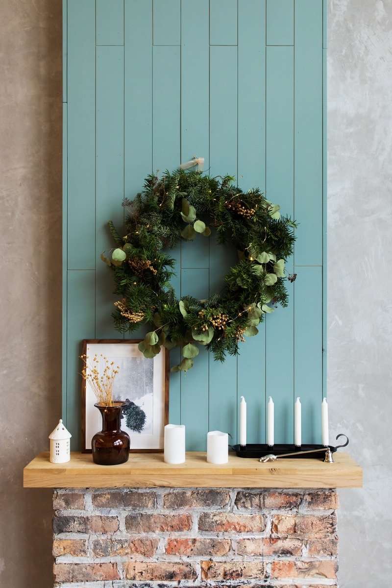Green wreath hanging above a fireplace mantel