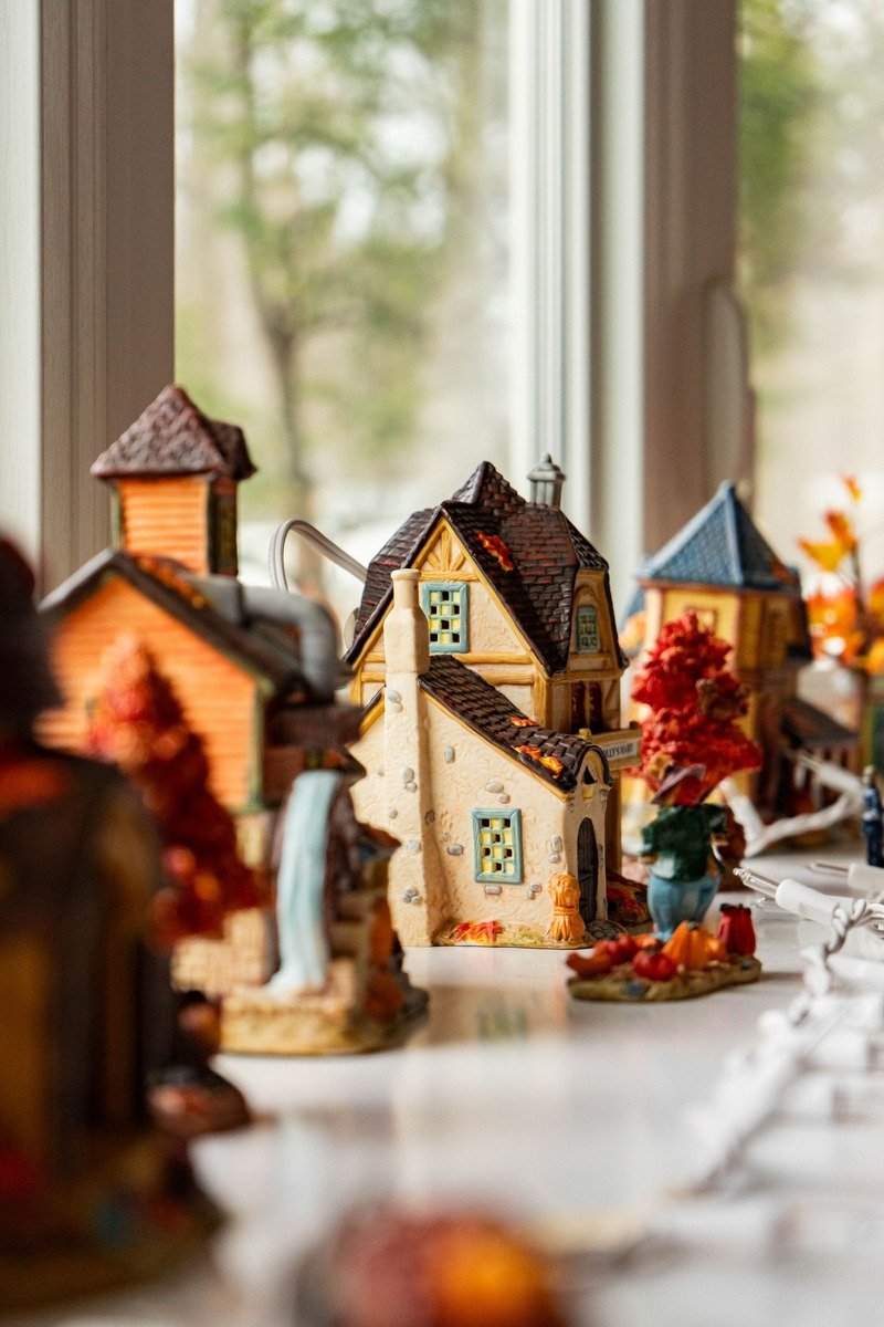 Small lit Christmas village houses on a windowsill at dusk