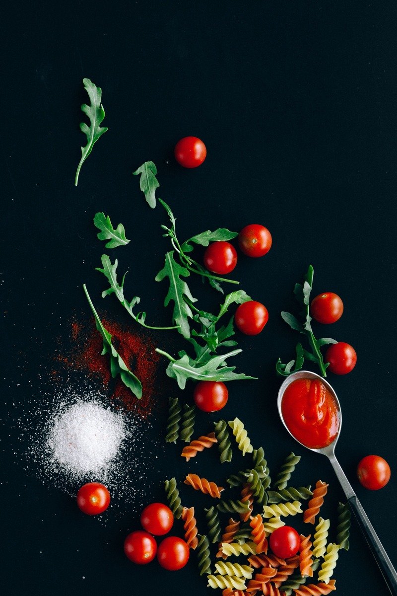 Italian pasta ingredients with tomatoes and sauce on a dark table