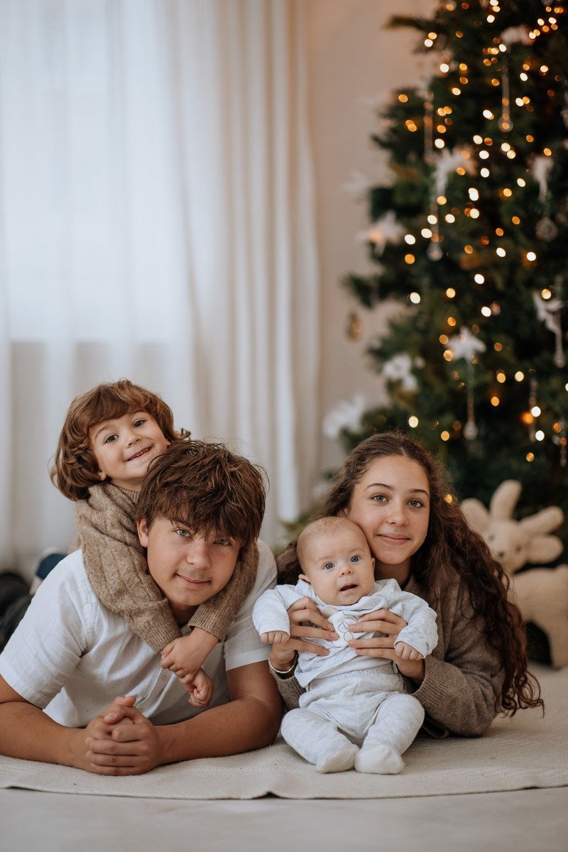 Family in neutral knit sweaters with one red accent piece