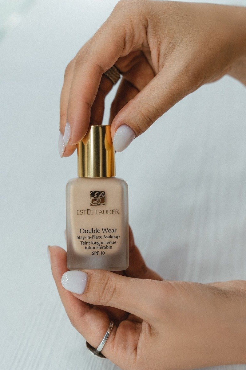 Glossy white light nails, hands holding a foundation bottle