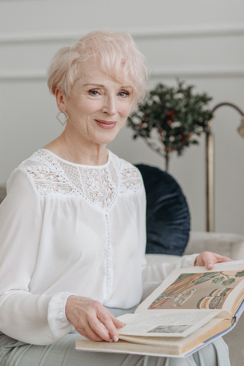 Woman over 50 with short wavy hair with a soft pink tint