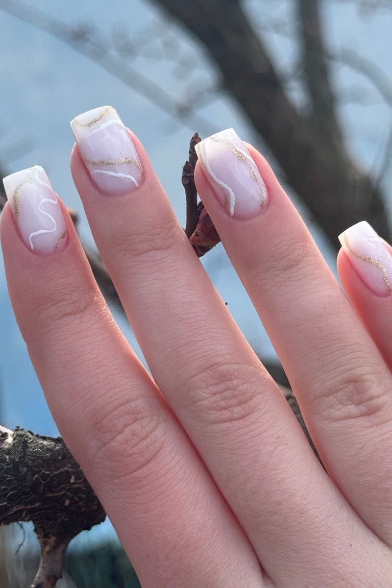 White marble-effect nails with thin gold veining, square shape outdoors