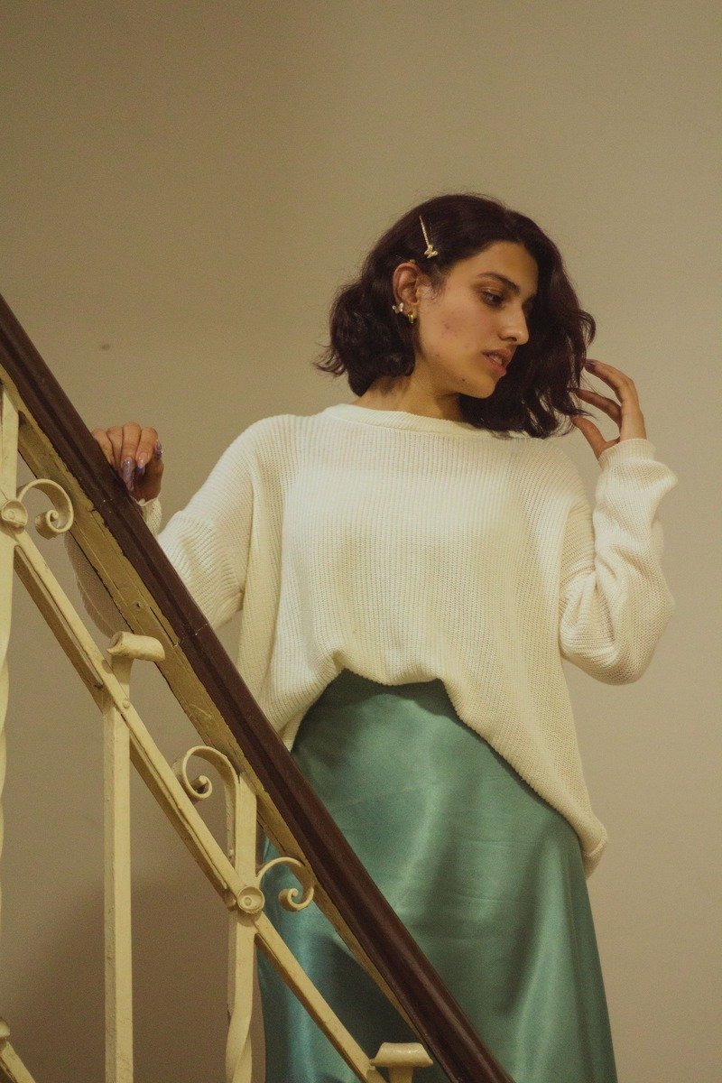Woman in an oversized sweater with a satin midi skirt and heels