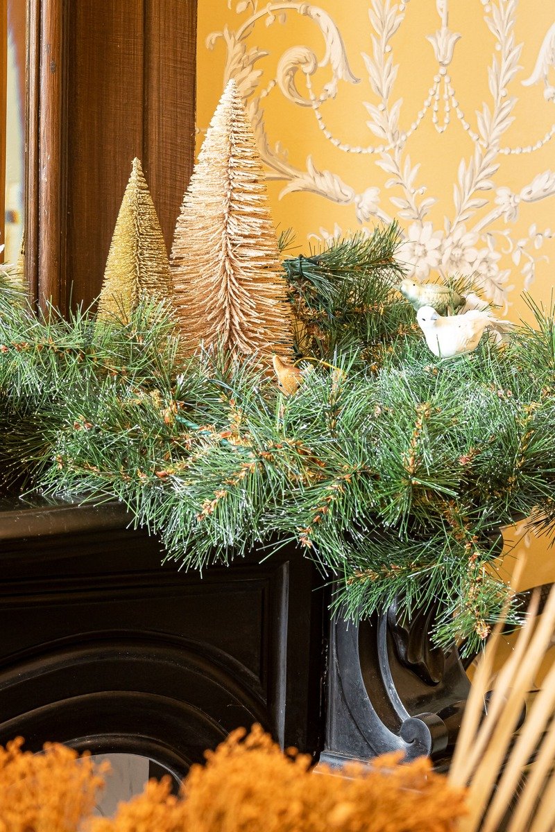 Greenery garland draped along a fireplace mantel