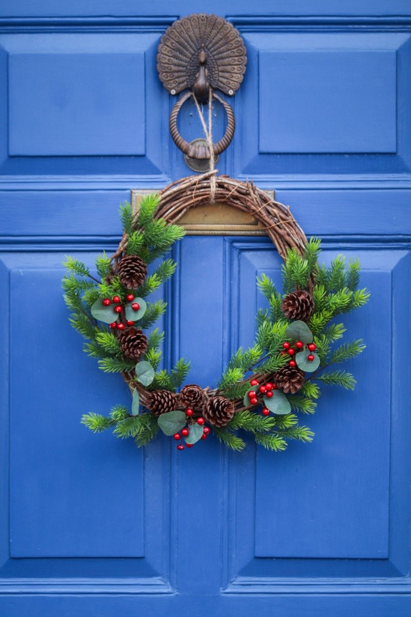 Pinecone and greenery Christmas wreath hanging on a door