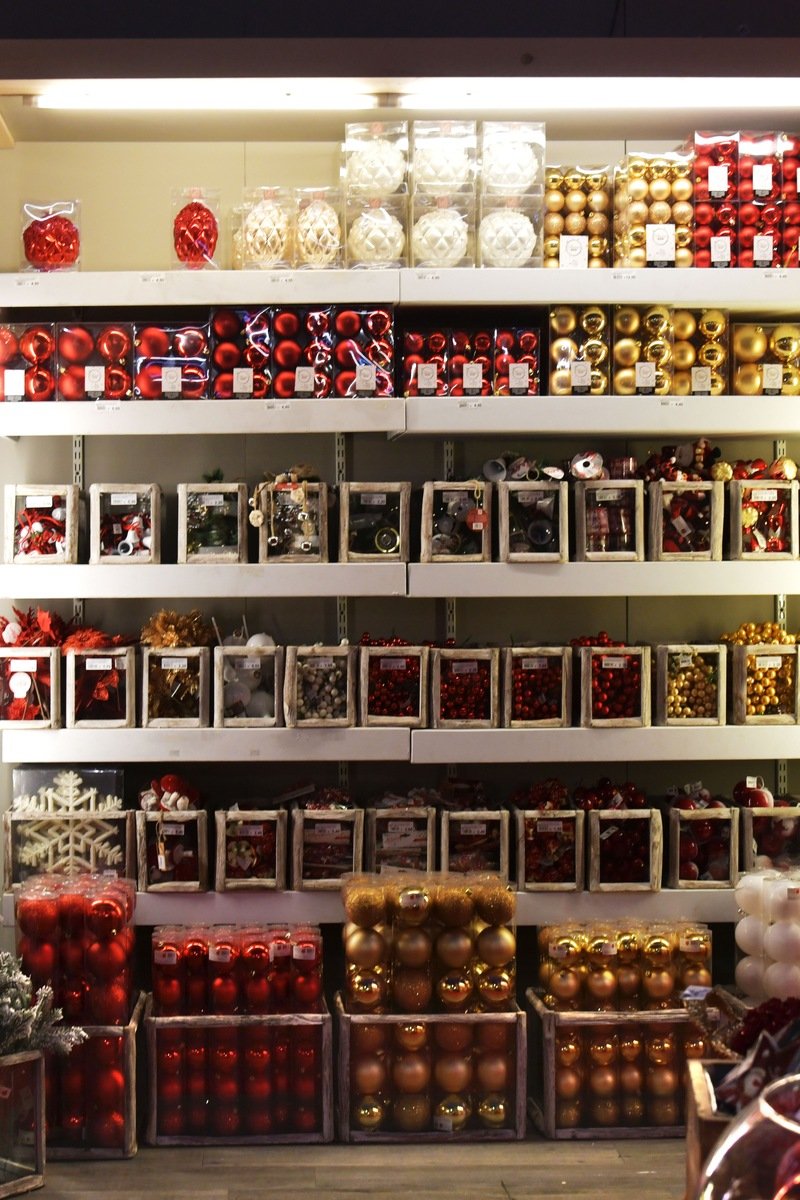 Shelves packed with red, gold, and white Christmas baubles inside a holiday ornament shop