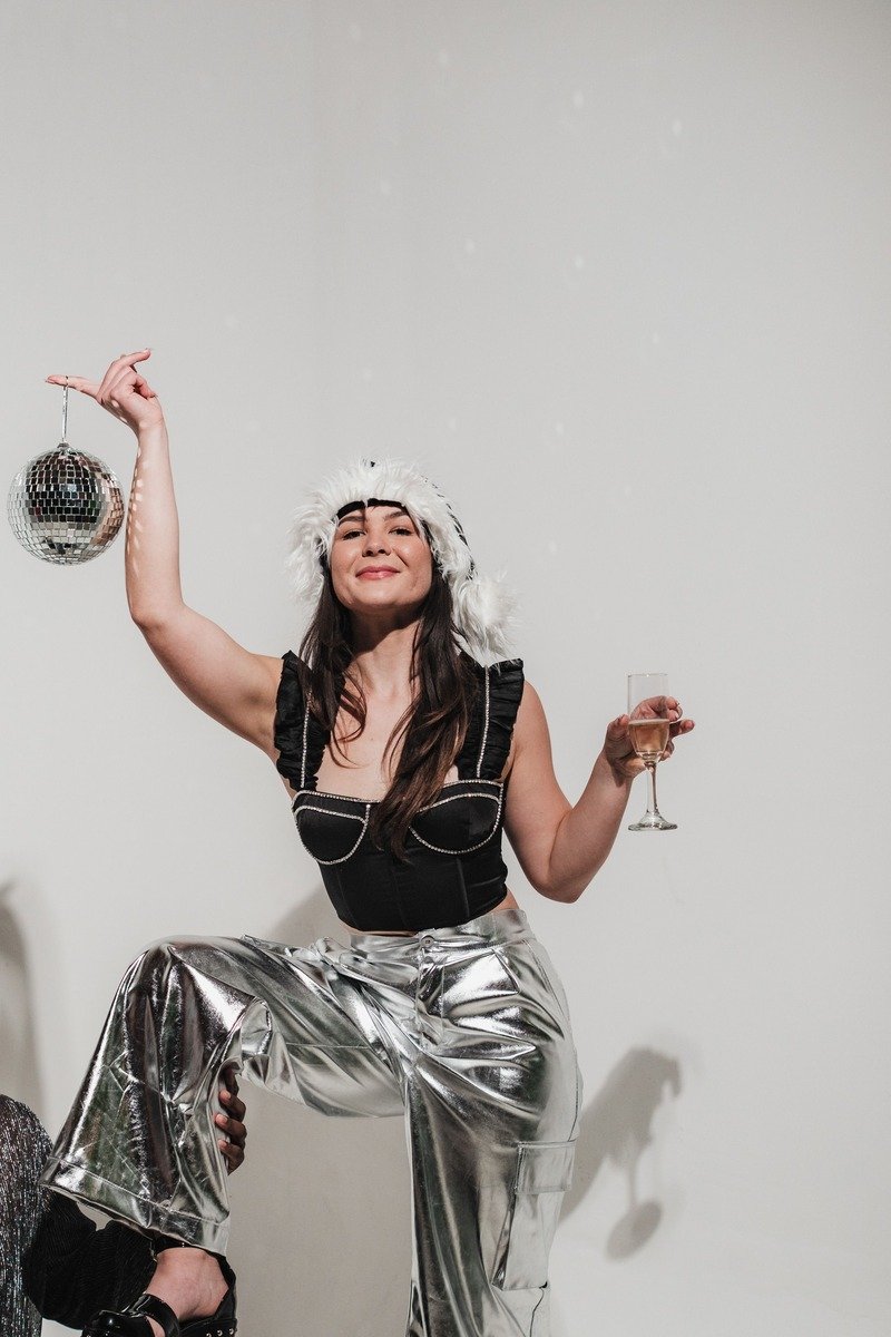 Woman in silver sequin pants with a black top holding a drink at midnight