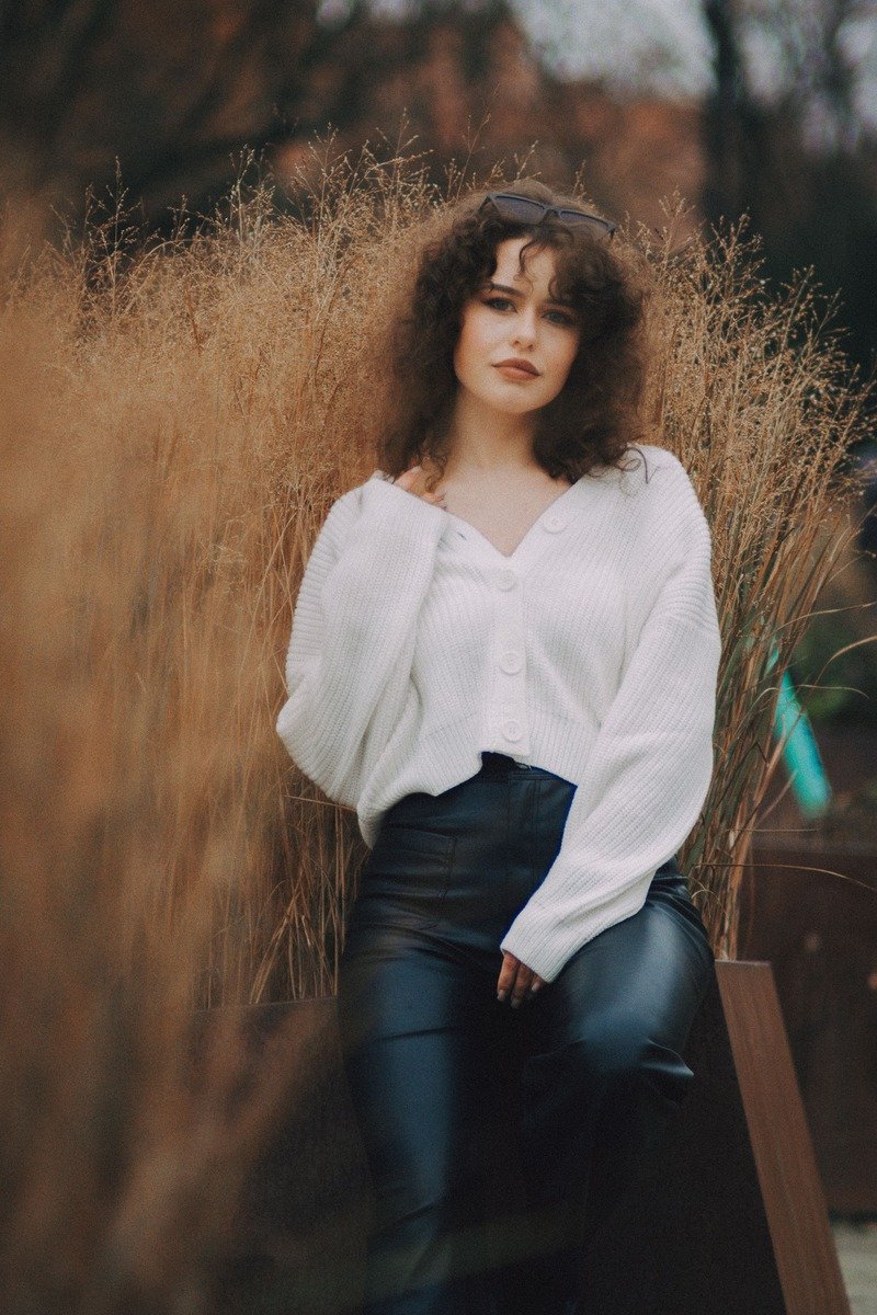 Woman in a cream oversized sweater with black leather pants
