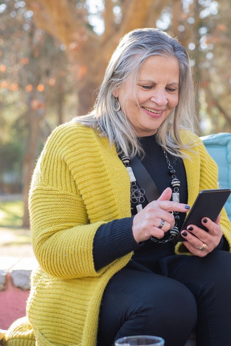 Woman over 50 in a yellow cardigan over a black top and trousers