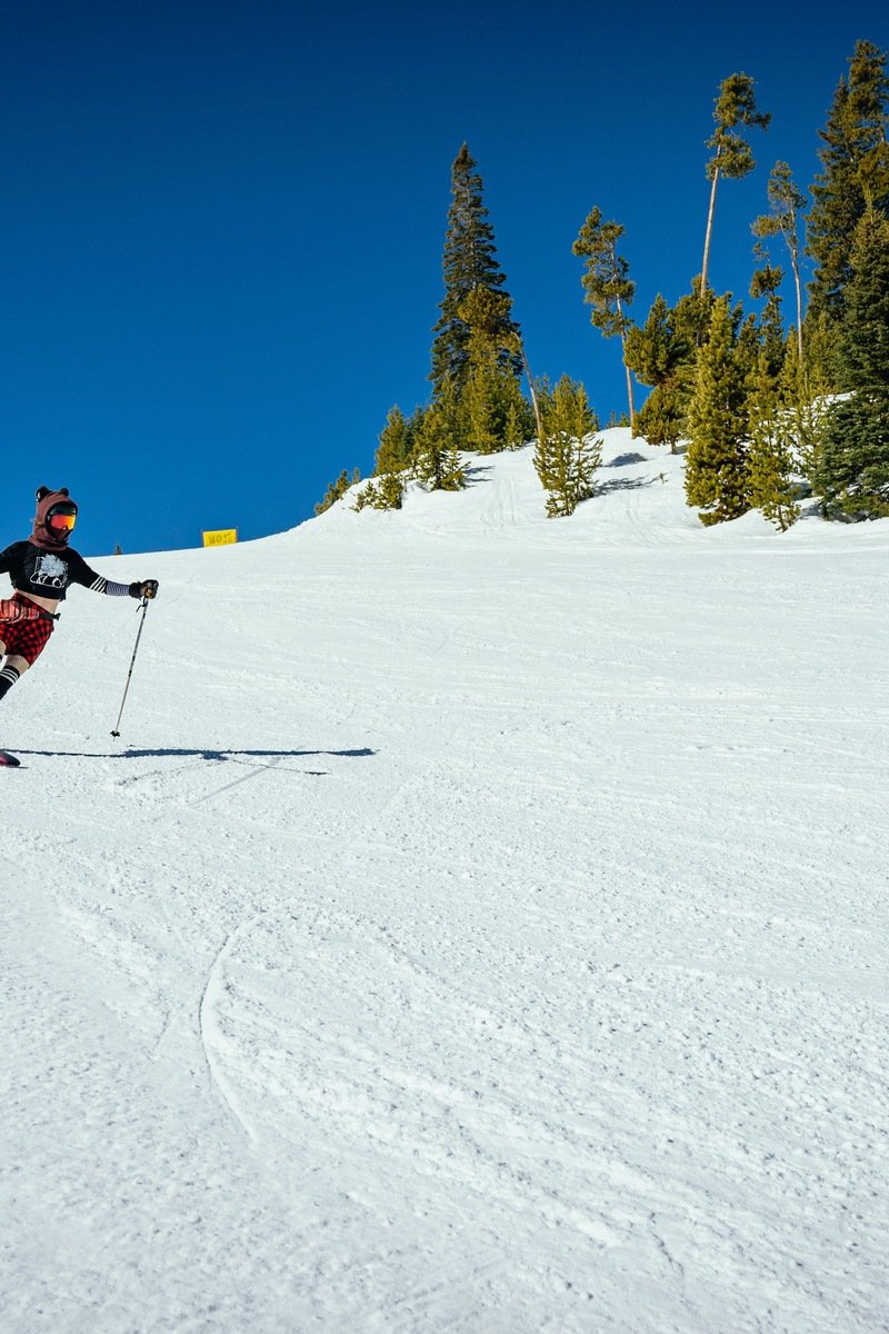 A skier carving down a groomed sunny slope