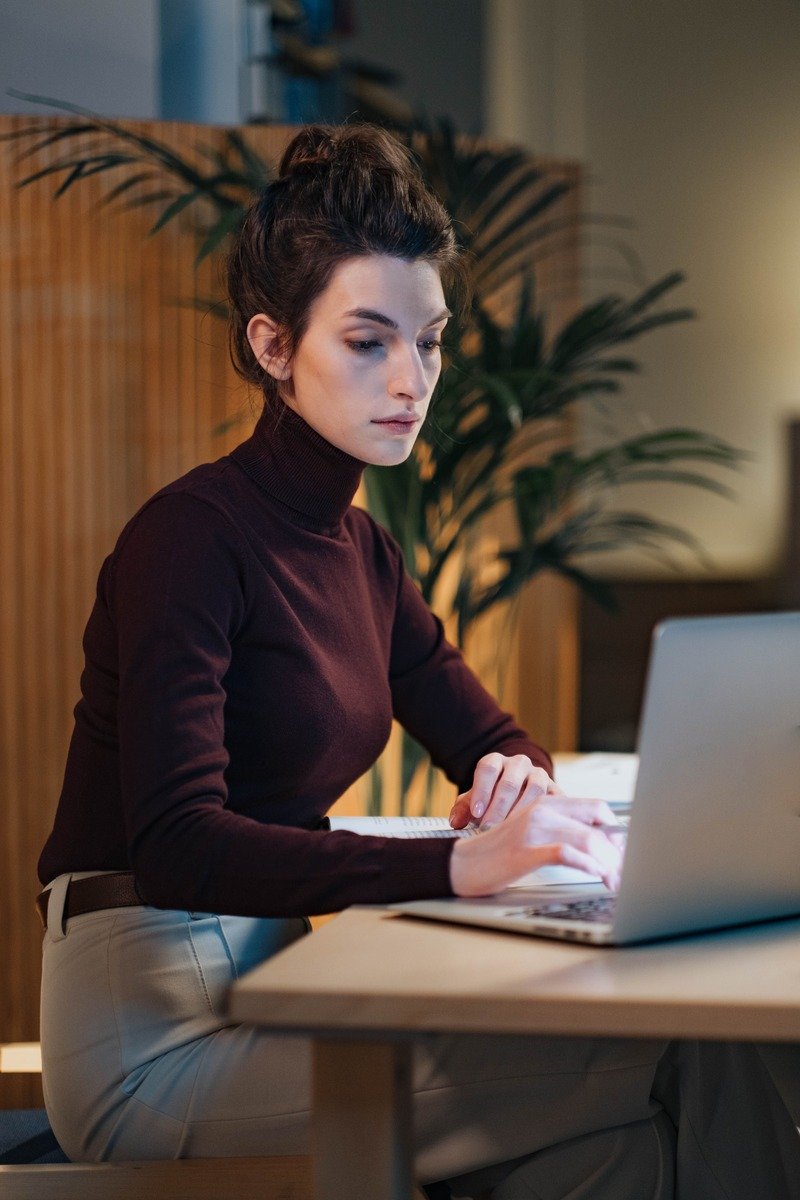 Woman in a turtleneck sweater and wool trousers at her desk