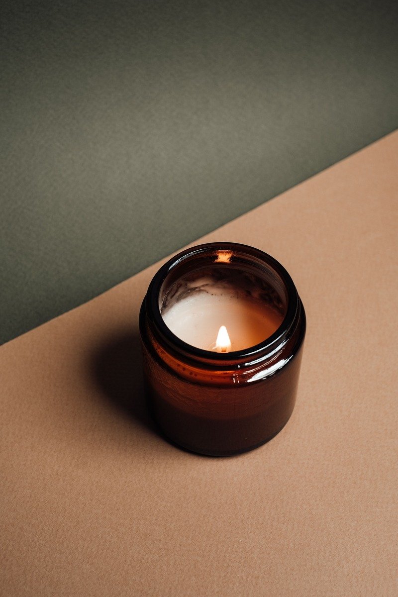 Scented candle in a pretty glass jar glowing