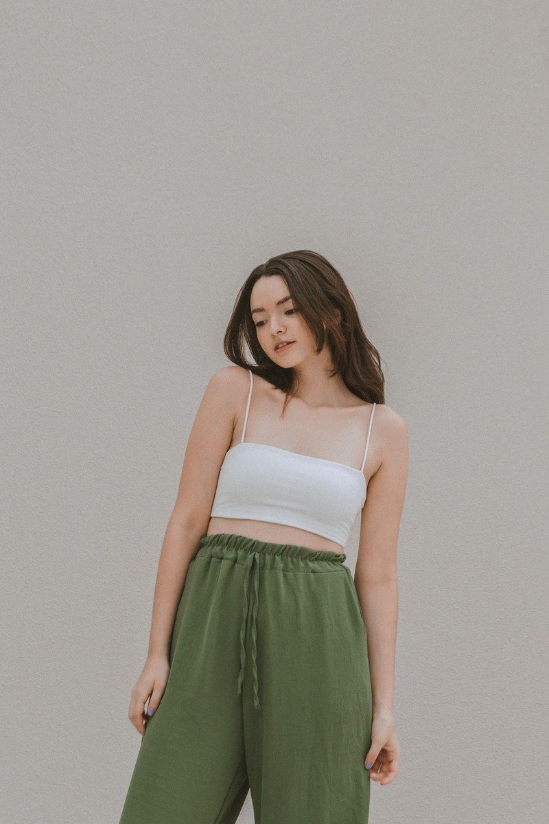 Woman in green wide leg pants and a white top