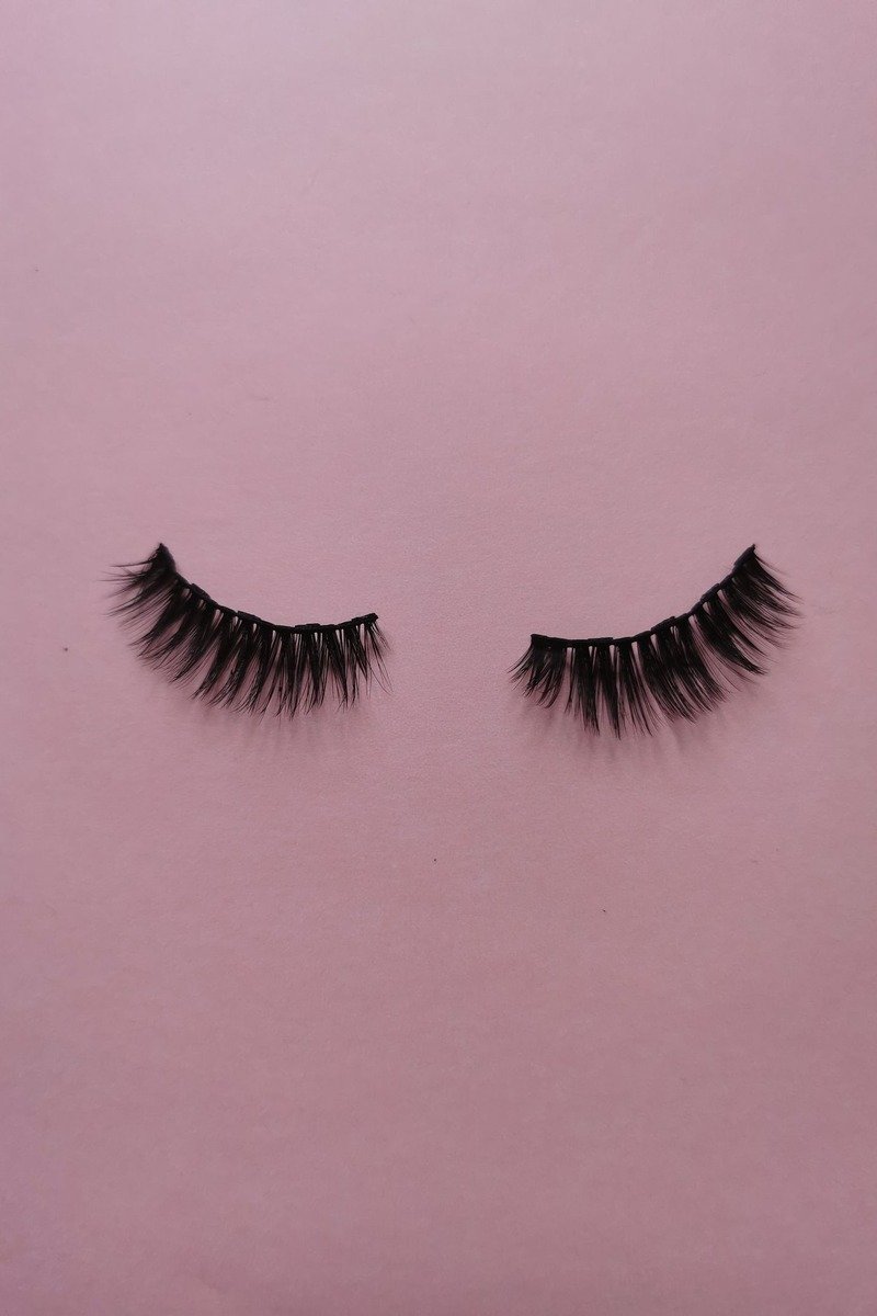 Subtle thin-band wispy strip lashes on a makeup table