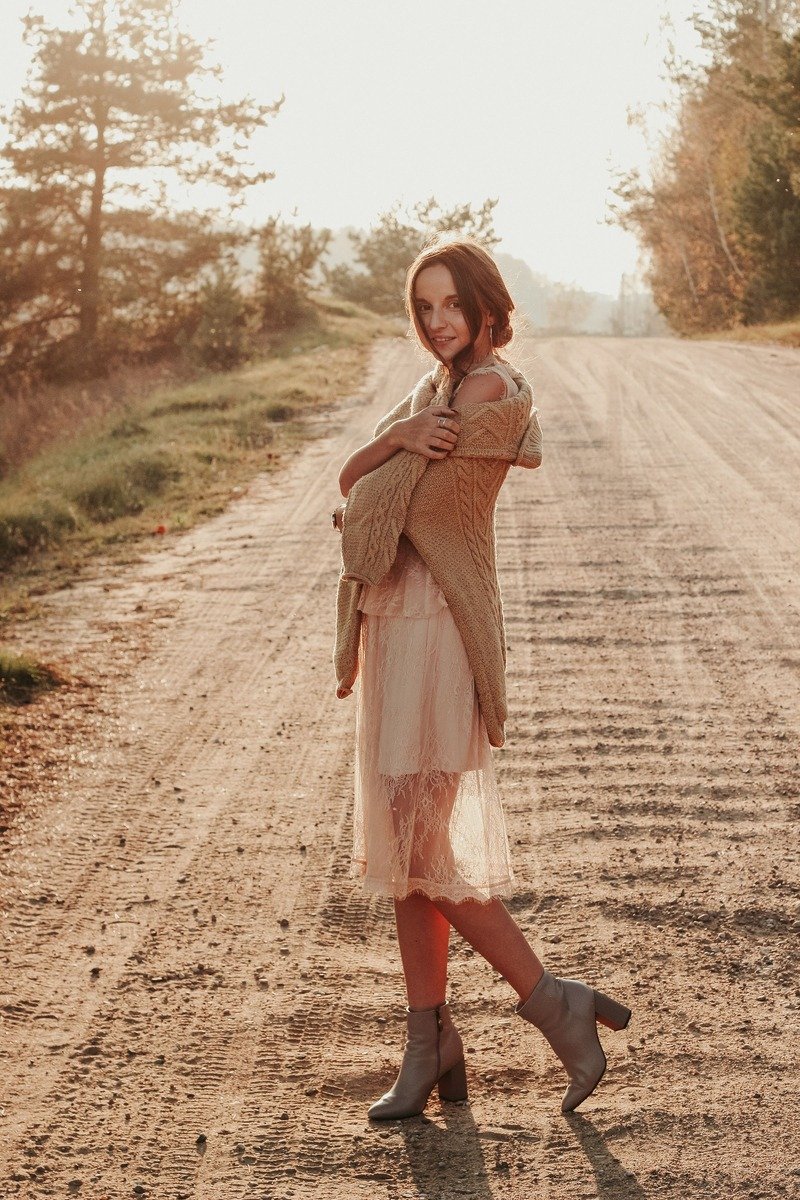 Woman in a chunky oversized sweater over a slip dress with boots