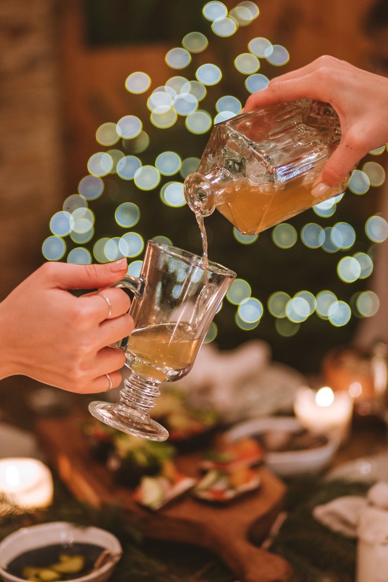 Mulled wine being poured into a glass mug at a cozy candlelit holiday table
