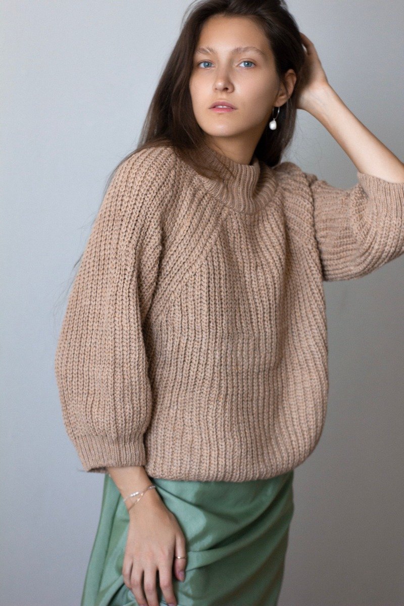 Woman in a chunky knit sweater with a satin skirt at work