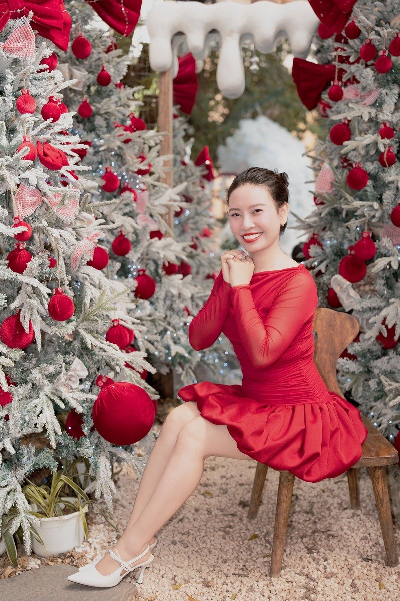 Woman in a red midi dress and heels posing by a Christmas tree